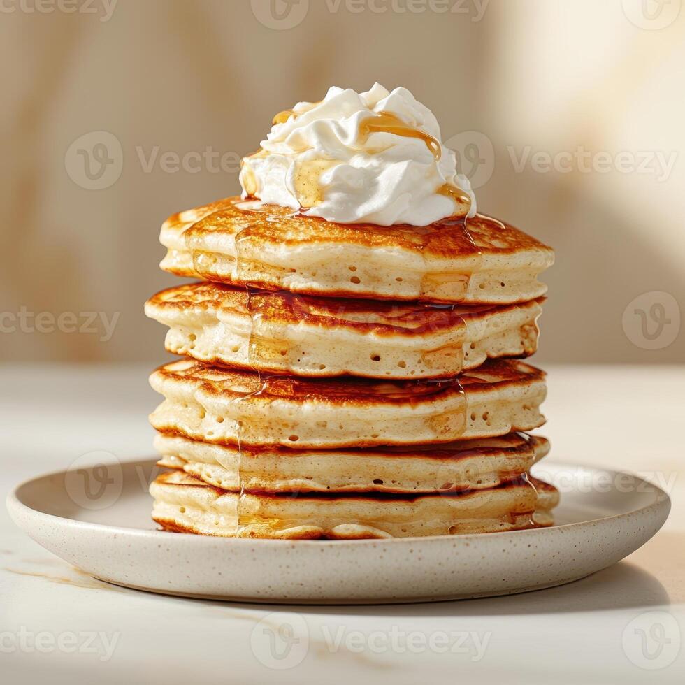 A stack of pancakes topped with whipped cream and syrup photo