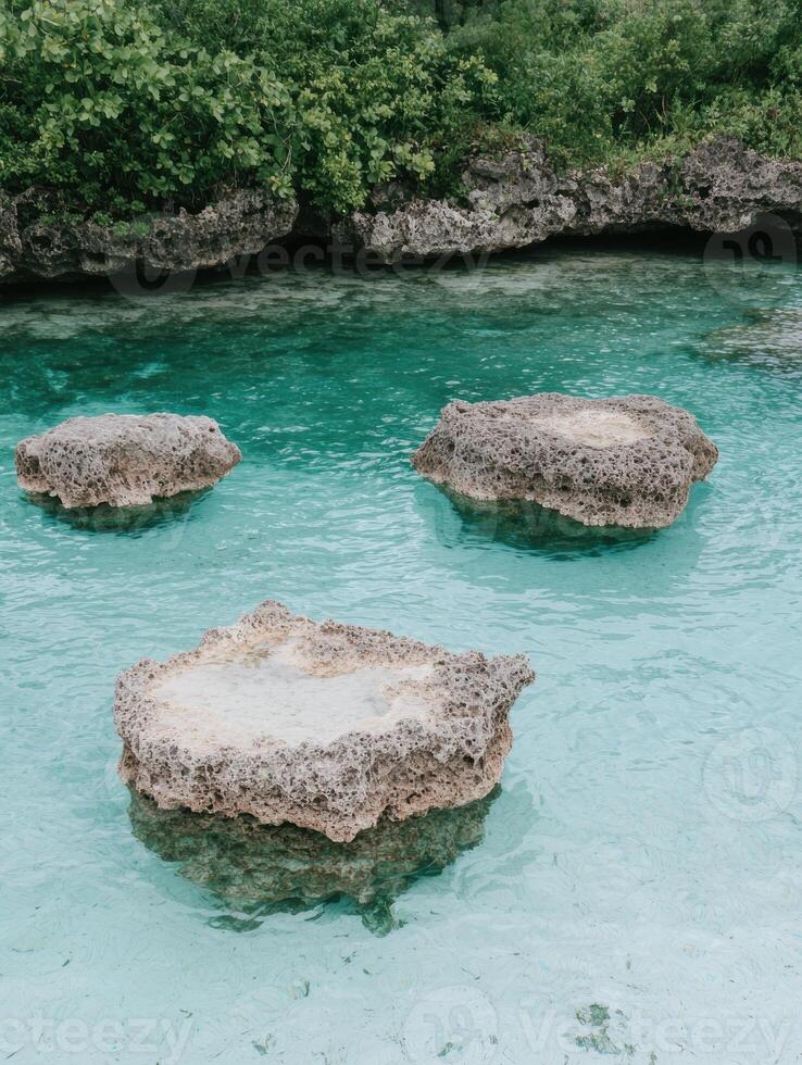 Three smooth rocks in a shallow turquoise lagoon photo