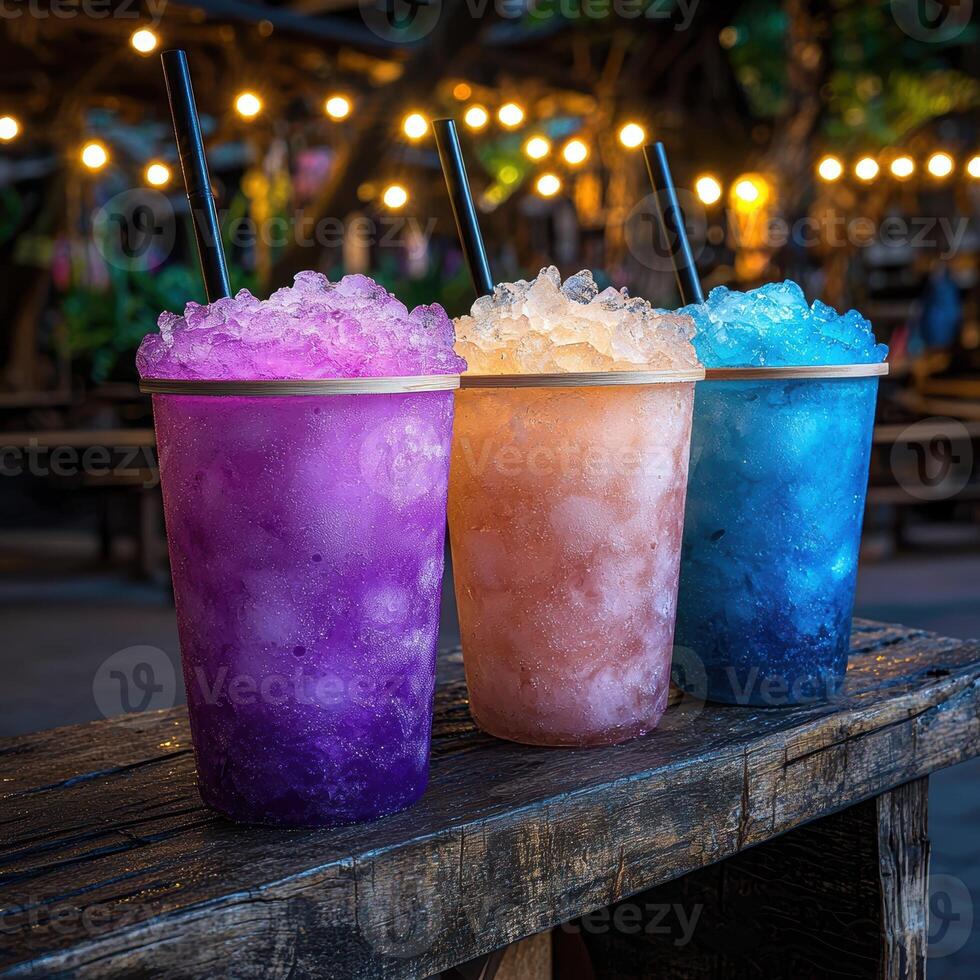 Three colorful icy drinks on a wooden table at night photo