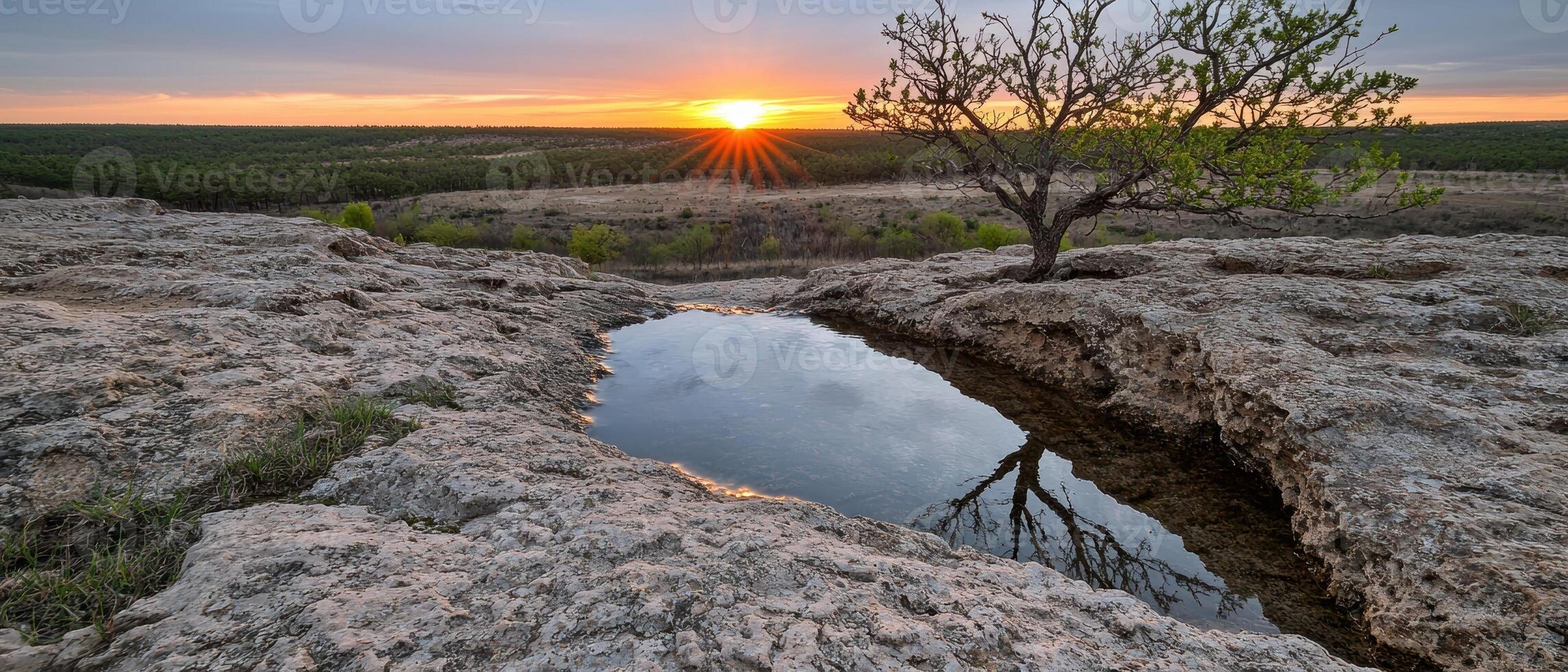Sunset over a tranquil landscape reflecting in a natural pool photo