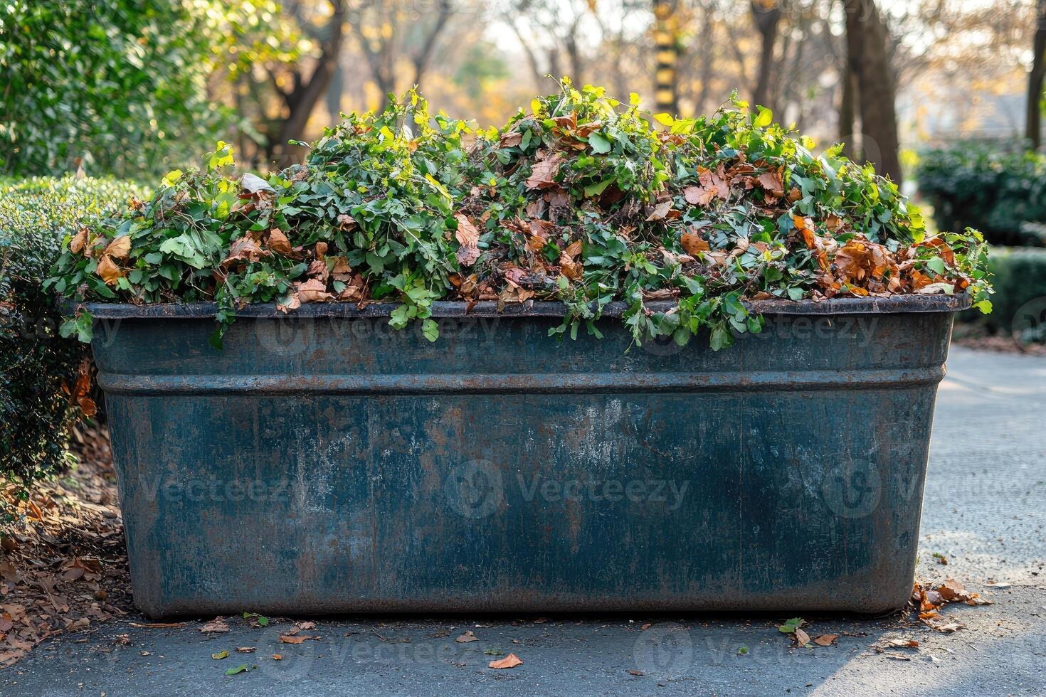 Large metal container overflowing with yard waste in park setting photo