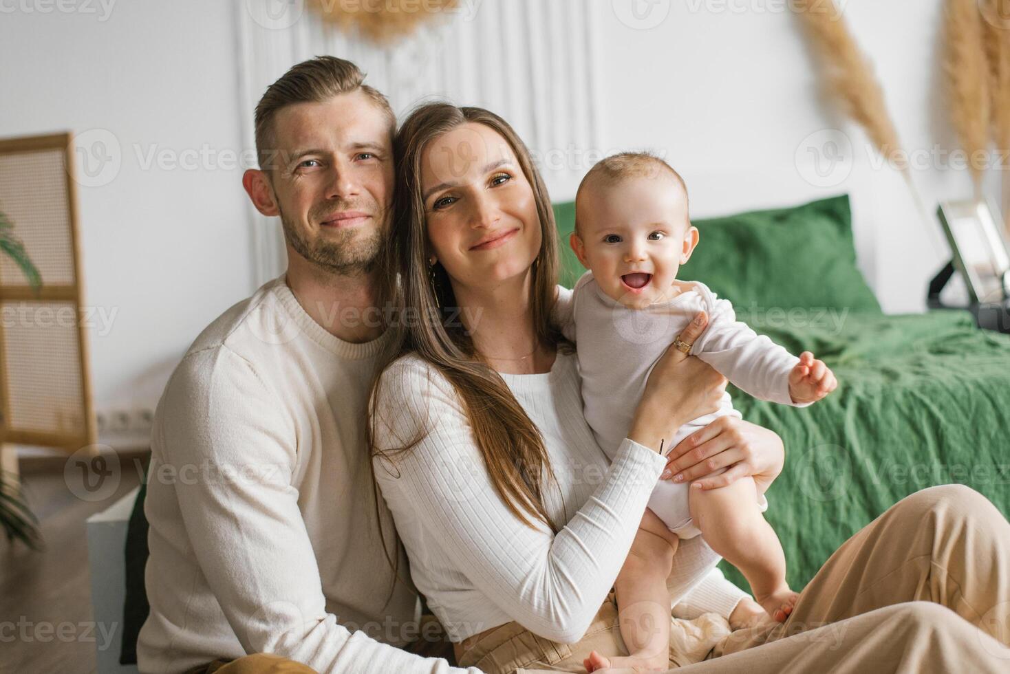 Portrait of Mom, Dad and six month old baby son in their arms spending time together in their cozy home photo