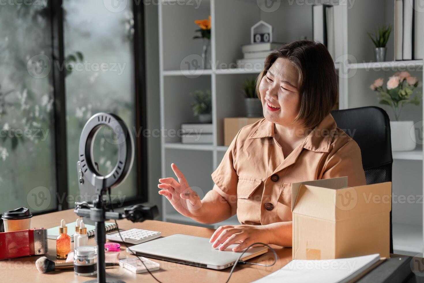 Young woman engaging with her audience while livestreaming skincare cream sales from a bright home office photo