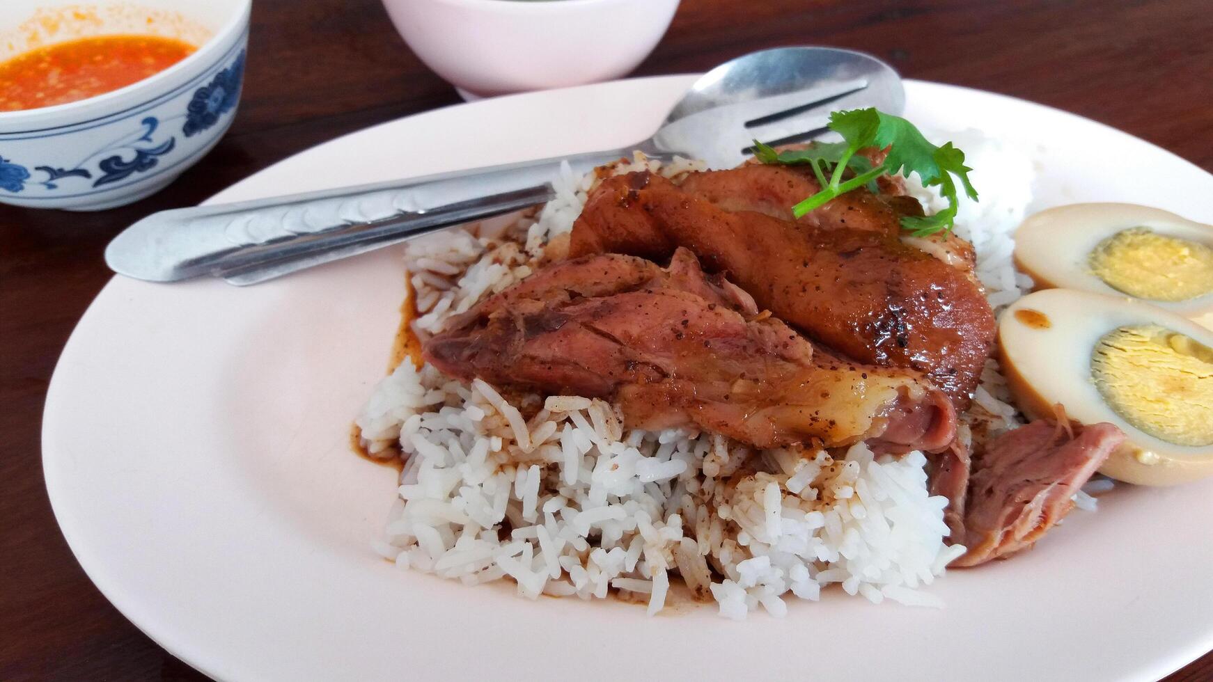 Close up Stewed pork leg with boiled egg on rice. Thai or famous food in Thailand on wood table. photo