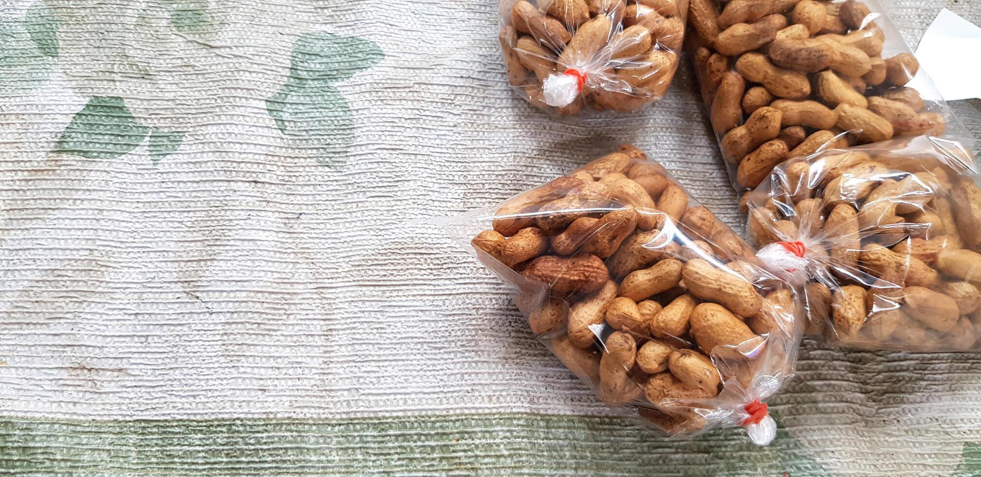Roasted peanuts in plastic bag for sale on old cotton at local street food market with left copy space. Food and Snack concept. photo