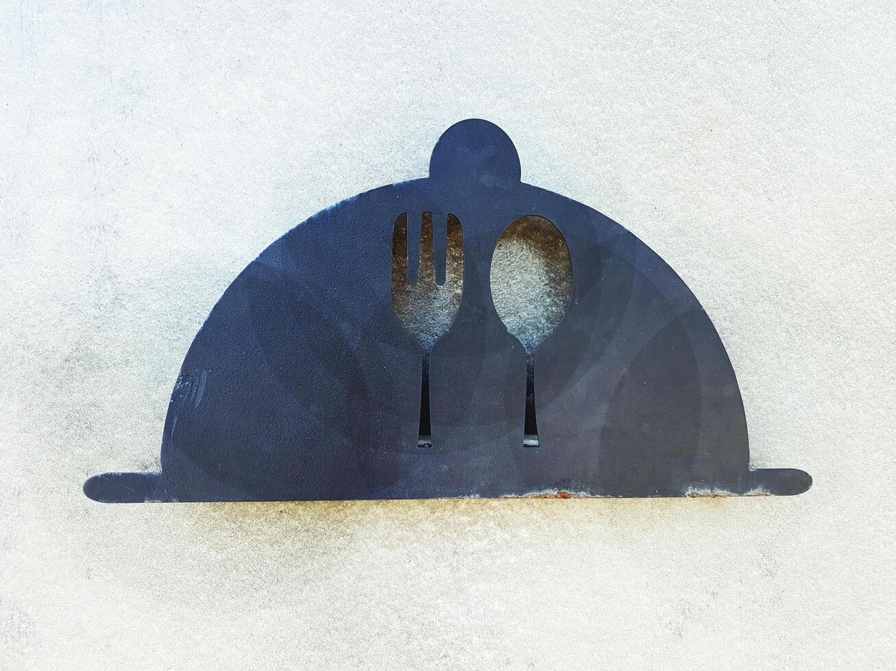 Spoon and fork sign made from steel or iron isolated on white cement wall background. Decoration, Vintage or Retro Object concept. photo