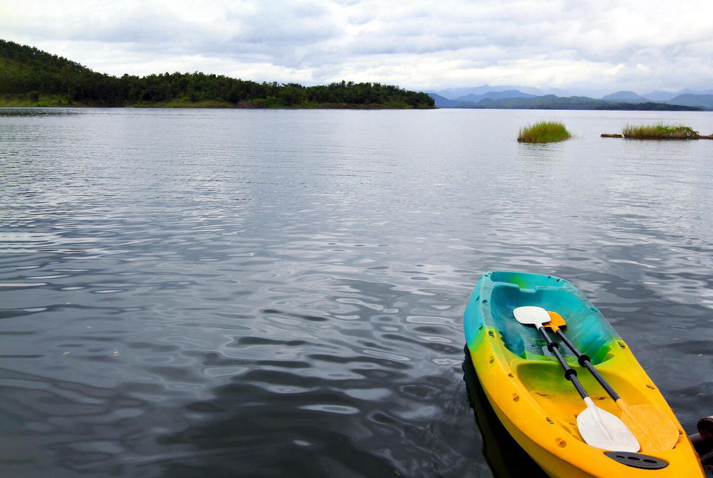 Colorful canoeing or kayak boat with two paddle or oar floating or parking on lake for tourist and customers rent with copy space at Srinagarind Dam lake, Kanchanaburi Province, Thailand. Activity photo