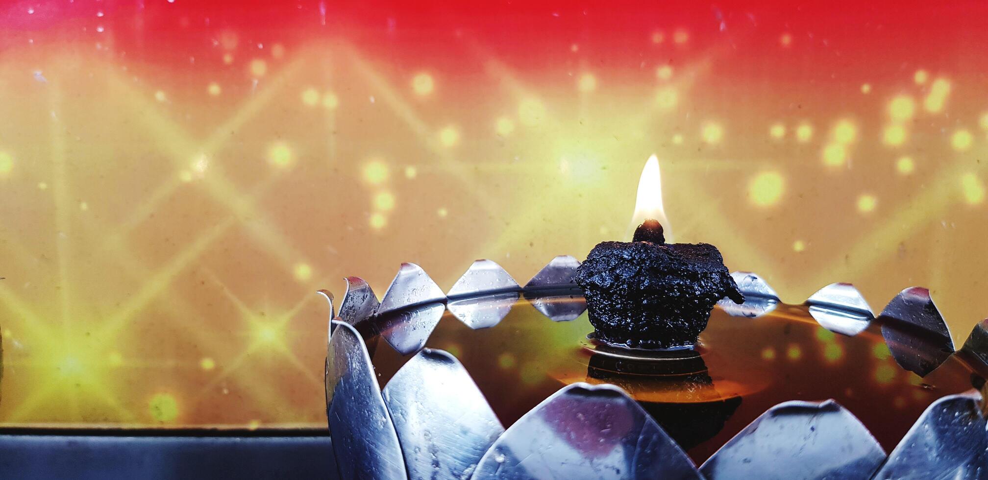 Close up flame, fire or candle light burning in oil lamp or lantern for worship or pay respect Buddha image and monk with red and yellow background and copy space at Thai temple. Art and Religion. photo