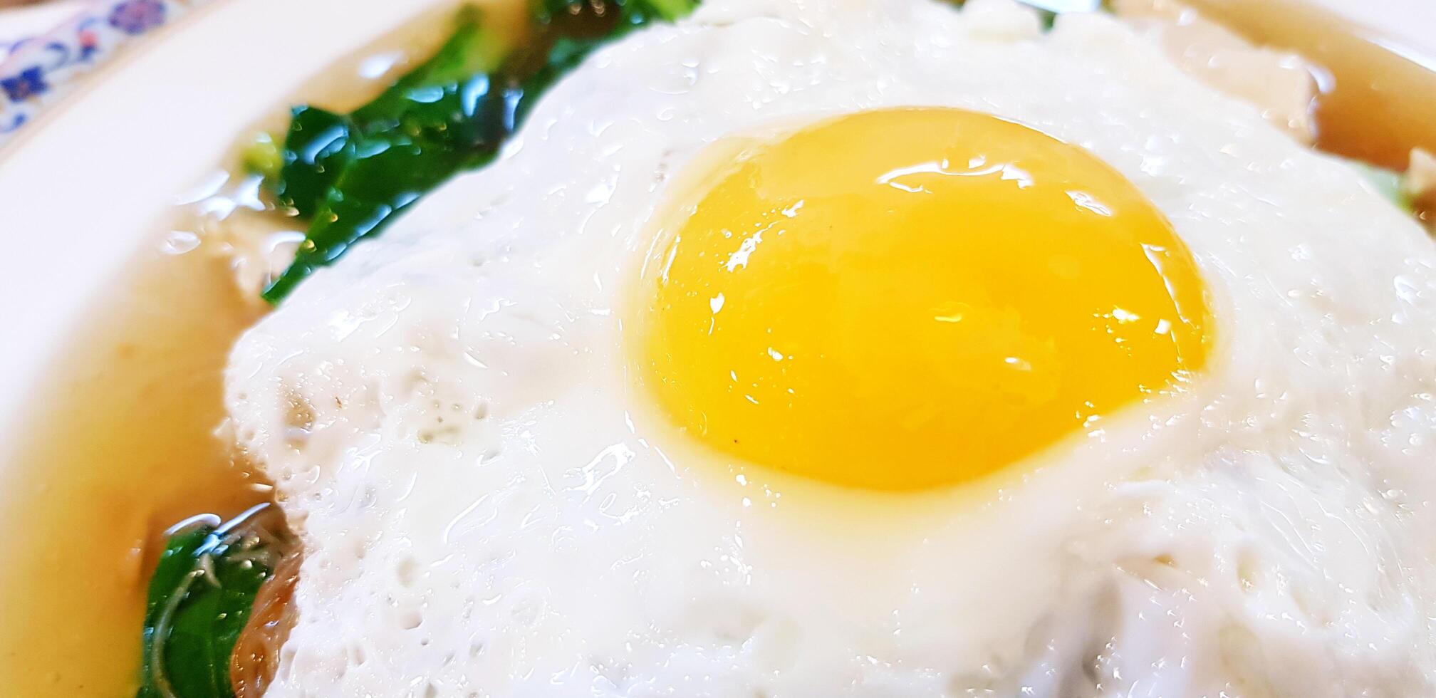 Close up fried egg and yolk on soup and vegetable in white plate with copy space. Healthy or Diet food and Protein concept. photo