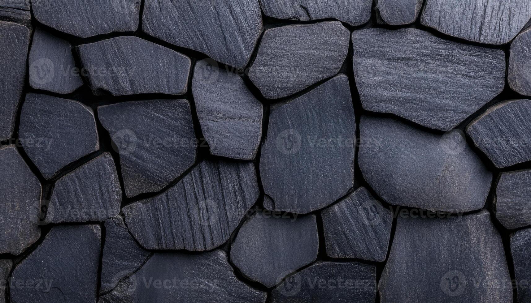 Dark slate stones of different sizes are arranged closely to form a textured wall surface photo