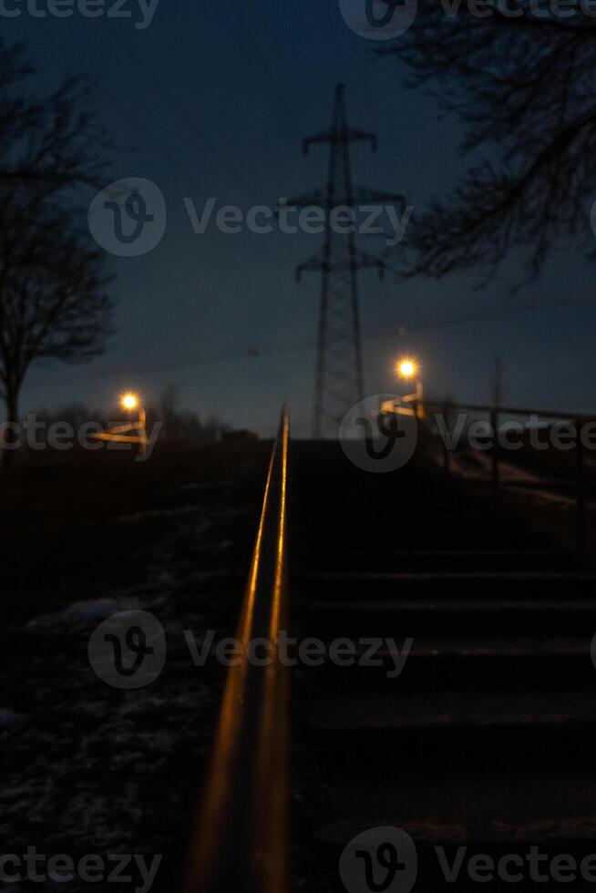 The steps are up, the railing is illuminated by an orange street lamp. Evening photo