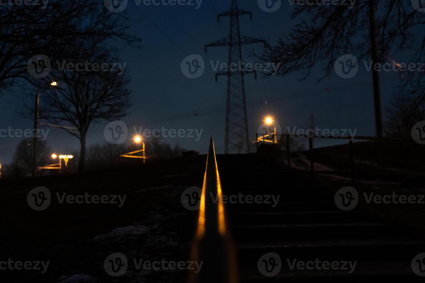The steps are up, the railing is illuminated by an orange street lamp. Evening photo