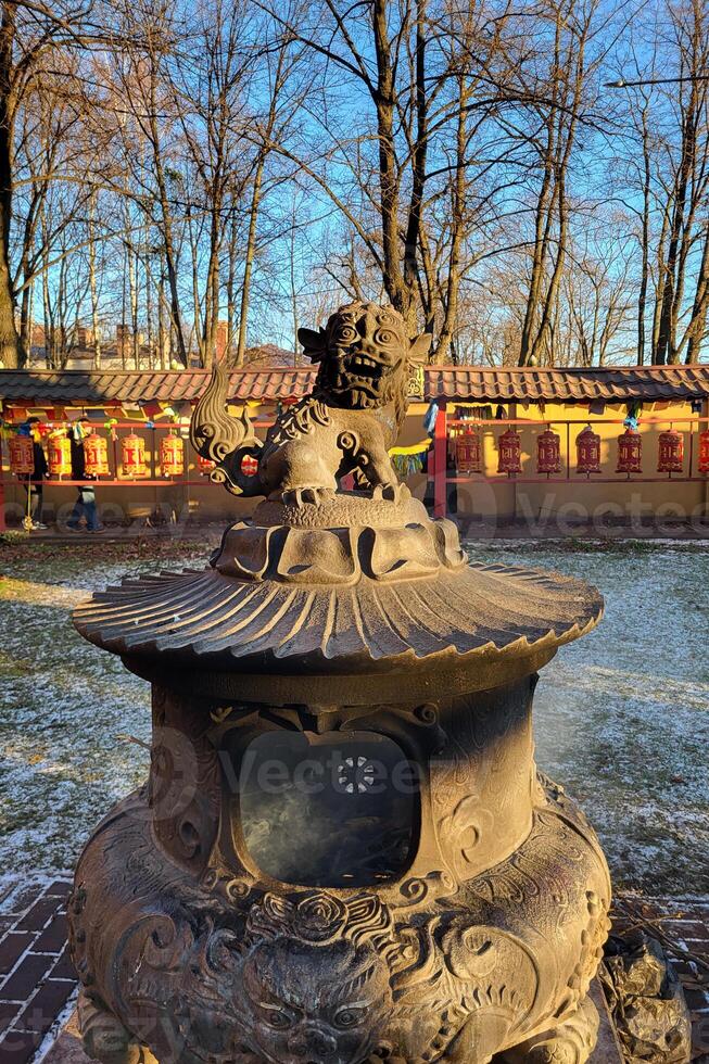 snow lion statue on top of a large bronze incense burner in the courtyard of a Buddhist Datsan Gunzechoinei photo