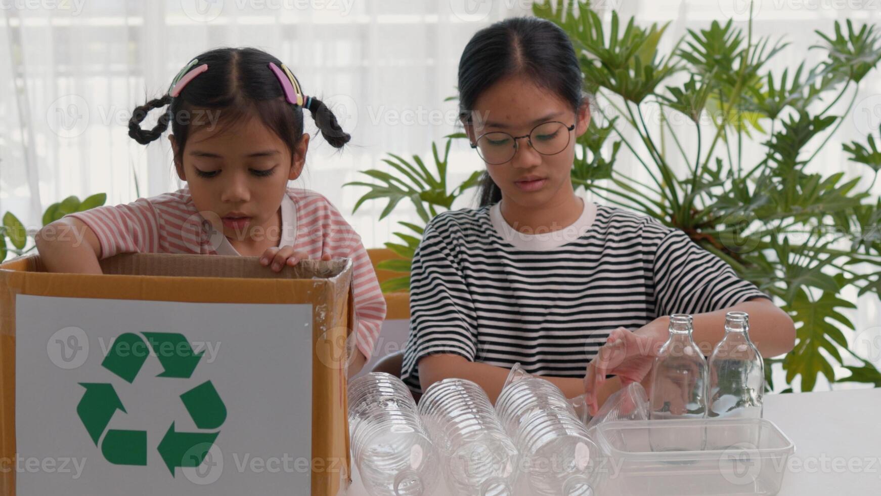 Asian siblings recycle household waste, Protect nature and save the environment. children learn to sort garbage by putting plastic bottles in the recycle photo