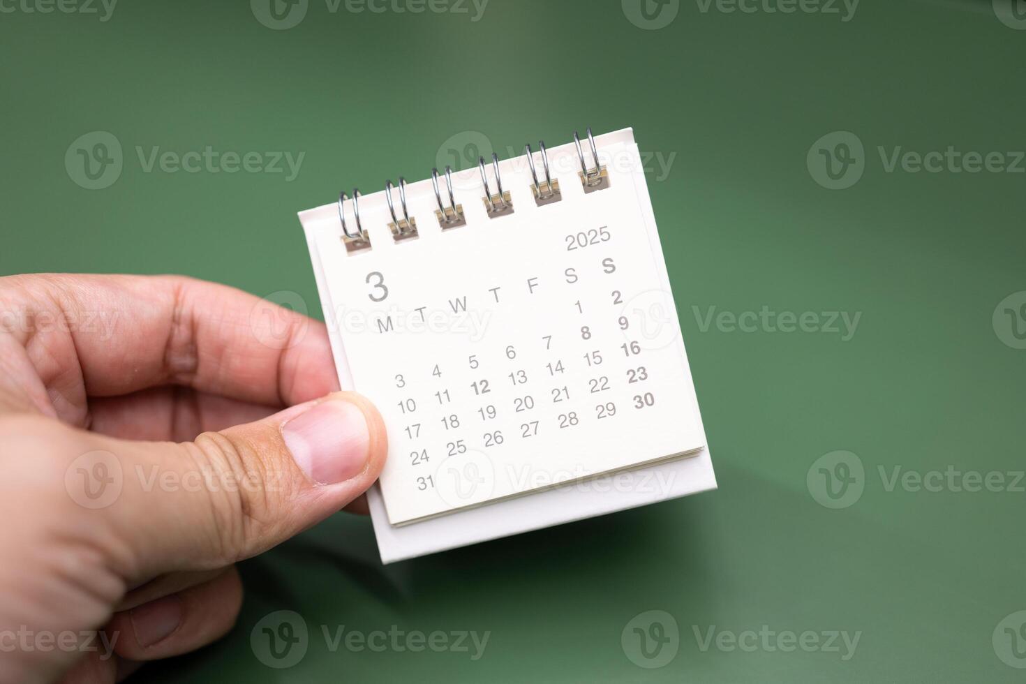 Hand holding mini calendar for MARCH 2025 background. Calendar concept with 2025 MAR calendar. photo