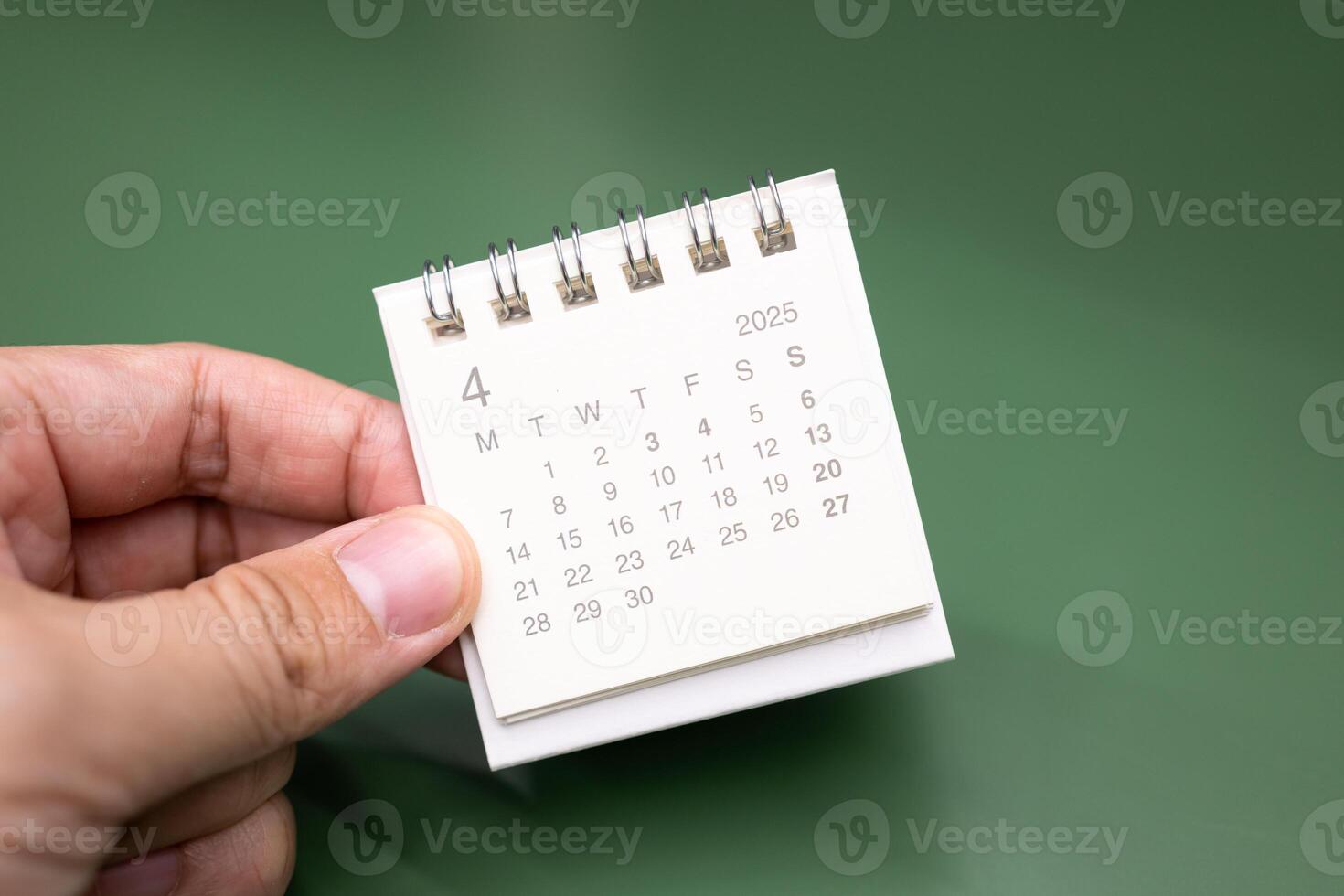 Hand holding mini calendar for 2025 APRIL background. Calendar concept with 2025 JAN calendar. photo