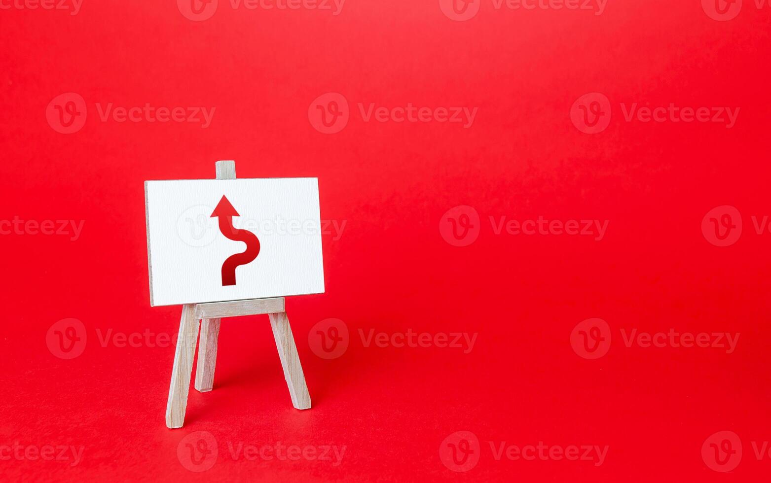 An easel with a curved arrow avoiding an obstacle. Deviation from route, side mission. Purposefulness and perseverance, confident movement towards the assigned goal. Maneuvering, taking right action. photo