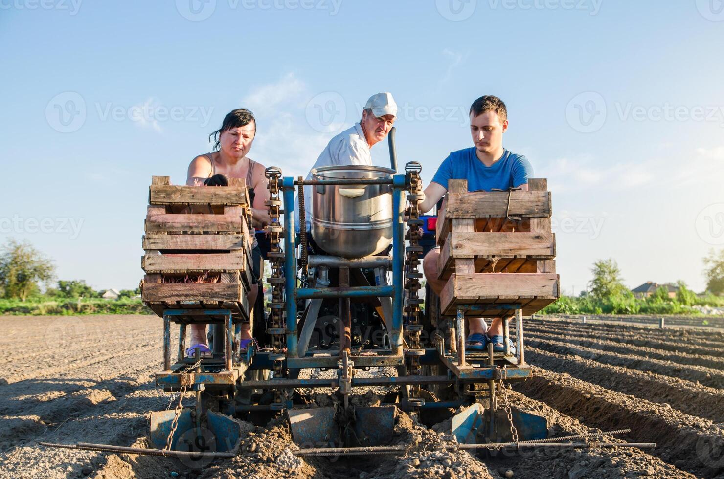 Farmer workers on a tractor plant potato seeds. Automation of process of planting potatoes seeds. High efficiency and speed. Agroindustry and agribusiness. New technological solutions to simplify work photo