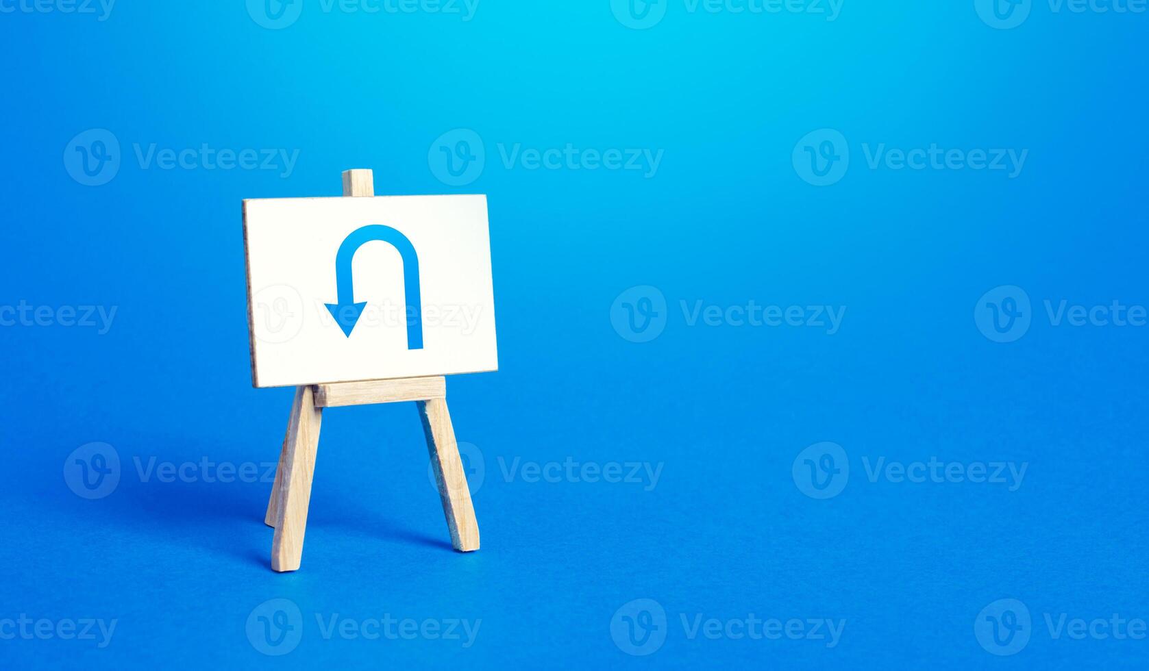 Easel with arrow turning back. Change plans, circumstances. Tactical retreat. Avoiding problems, reducing risks. Reassessment of actions. Break a promise. Return to source. Step back. Find other way. photo