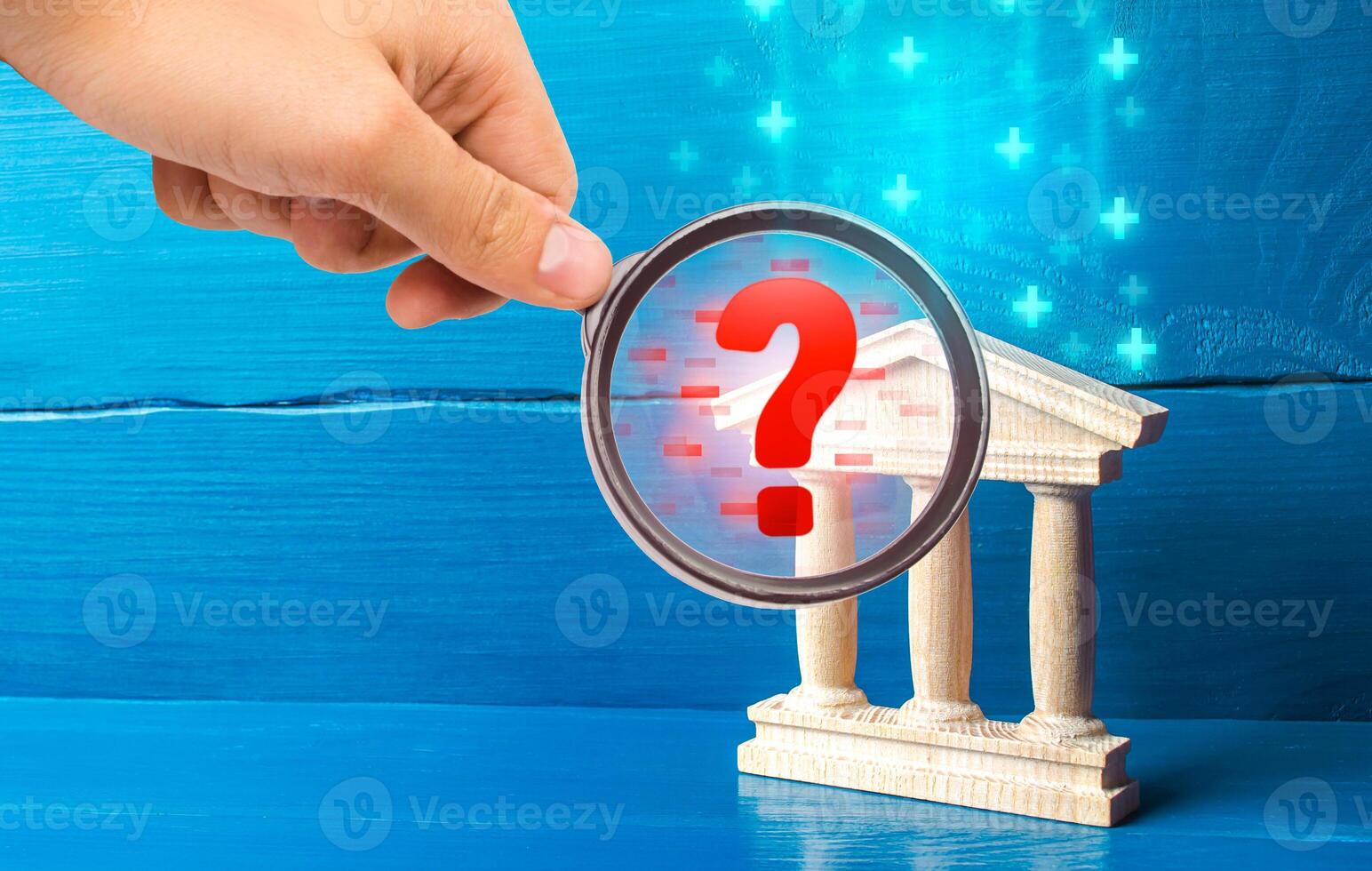 A hand with a magnifying glass inspects bank and finds violations. Audit of commercial banks. Stop money laundering and sanctions evasion. Liquidity, threat of bankruptcy collapse of financial system. photo