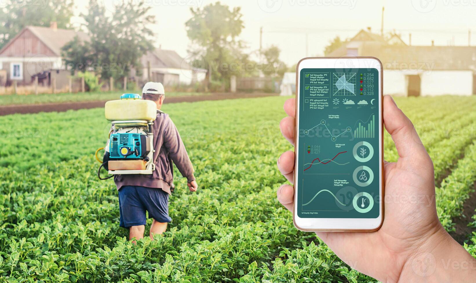 A hand with a phone on background of a farmer with agriculture smoke fog spraying machine. Crop plant care and protection from pests and fungal infection. Control of use of chemicals growing food. photo