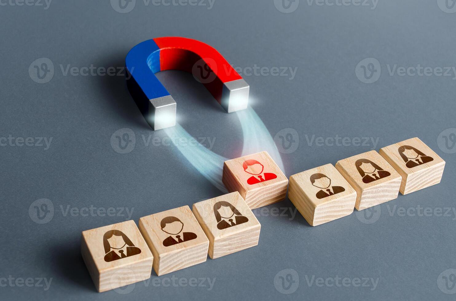 The magnet pulls a red person figure out of the row. Luring concept. Hiring best candidate. Poaching participants from other company. Selection for a management position on a competitive basis. photo