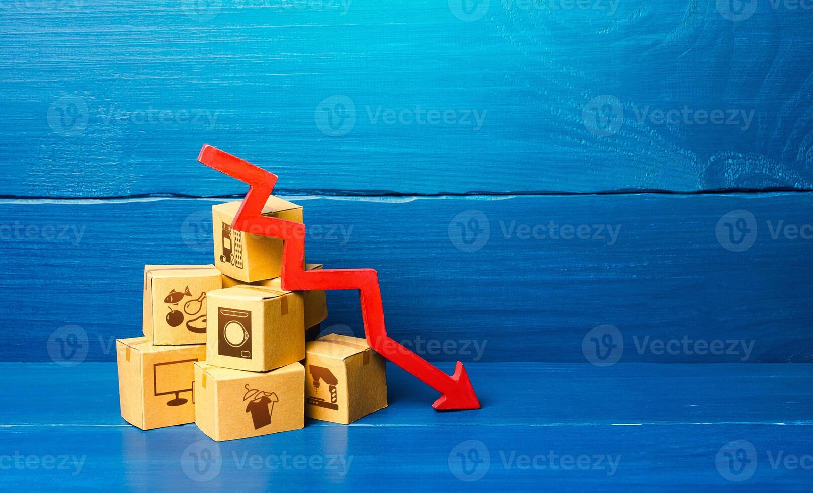 Cardboard boxes and red down arrow. Decline in sales and production volumes. Depressed economy. Low business activity. Economic recession, skepticism and pessimism. Competitiveness of national goods. photo