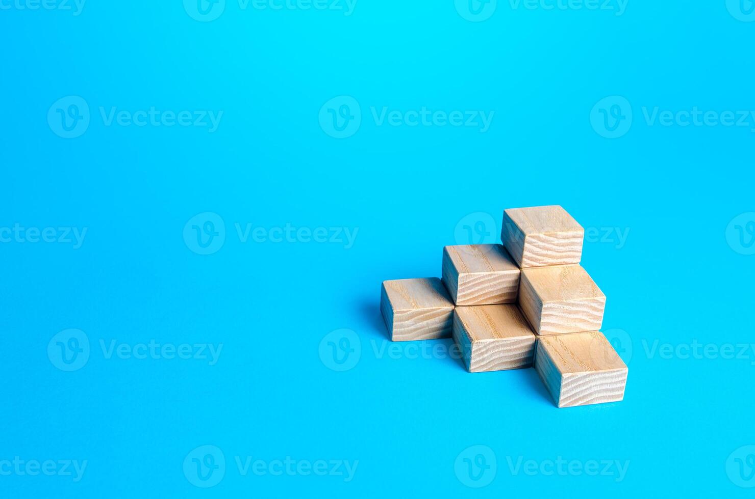 Wooden blocks pyramid on a blue background. Minimalism. Simple shapes geometry. Slide for presentation. Copy space, place for text. Steps. photo