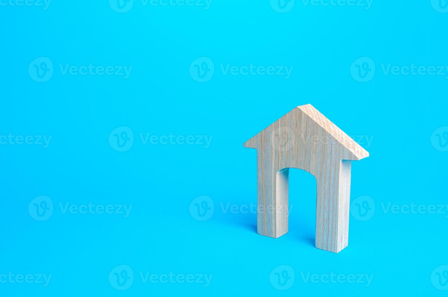 Wooden house figure on a blue background. Affordable comfortable housing concept, new home. Mortgage. Real estate, rent and sale. Realtor services. Copy Space photo