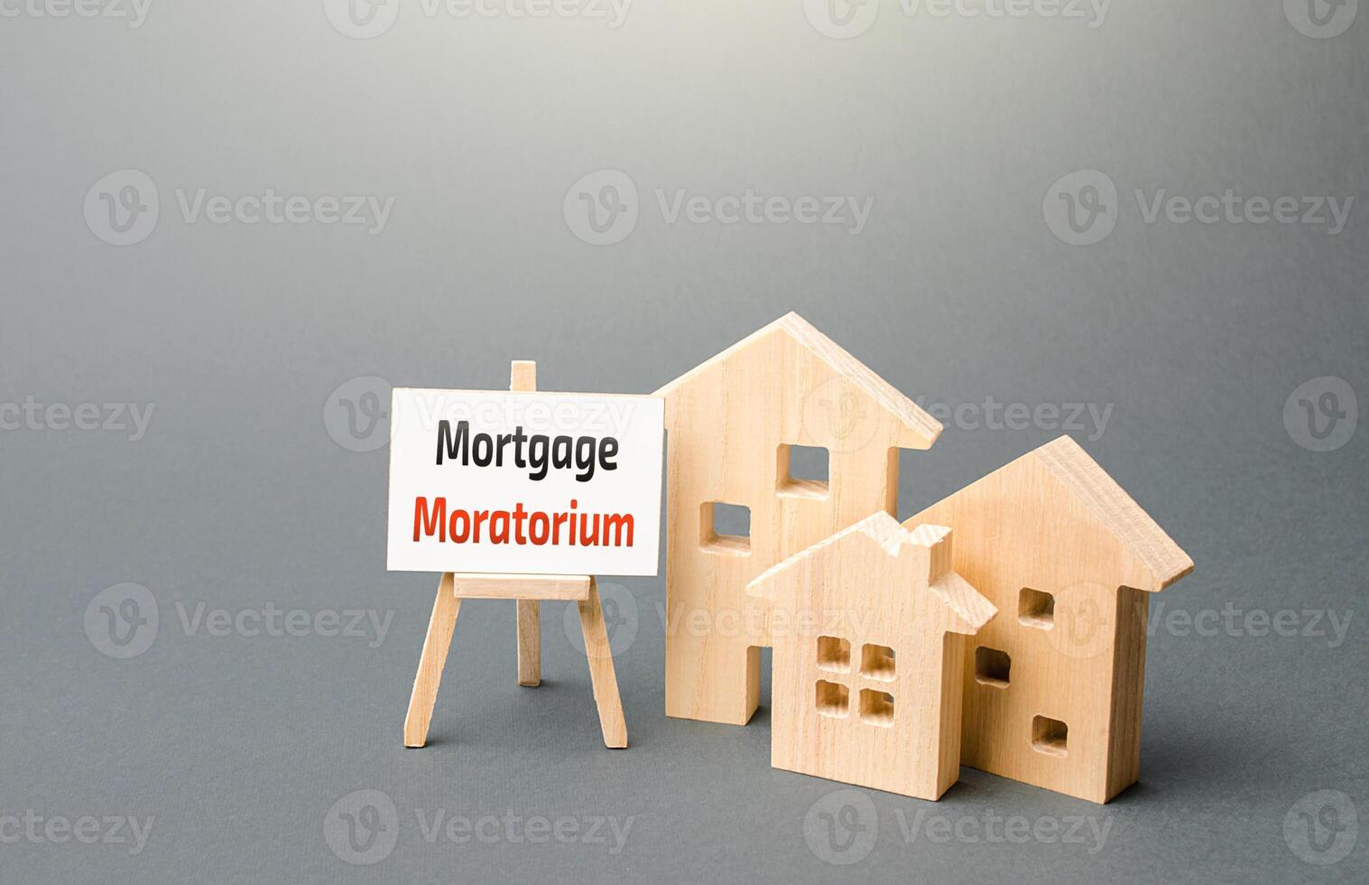 Houses figures and an easel sign with Mortgage Moratorium. Moratorium on loan repayments. Financial relief measures. Deferral of payments on debts, reliefs of debt burden during the crisis. photo