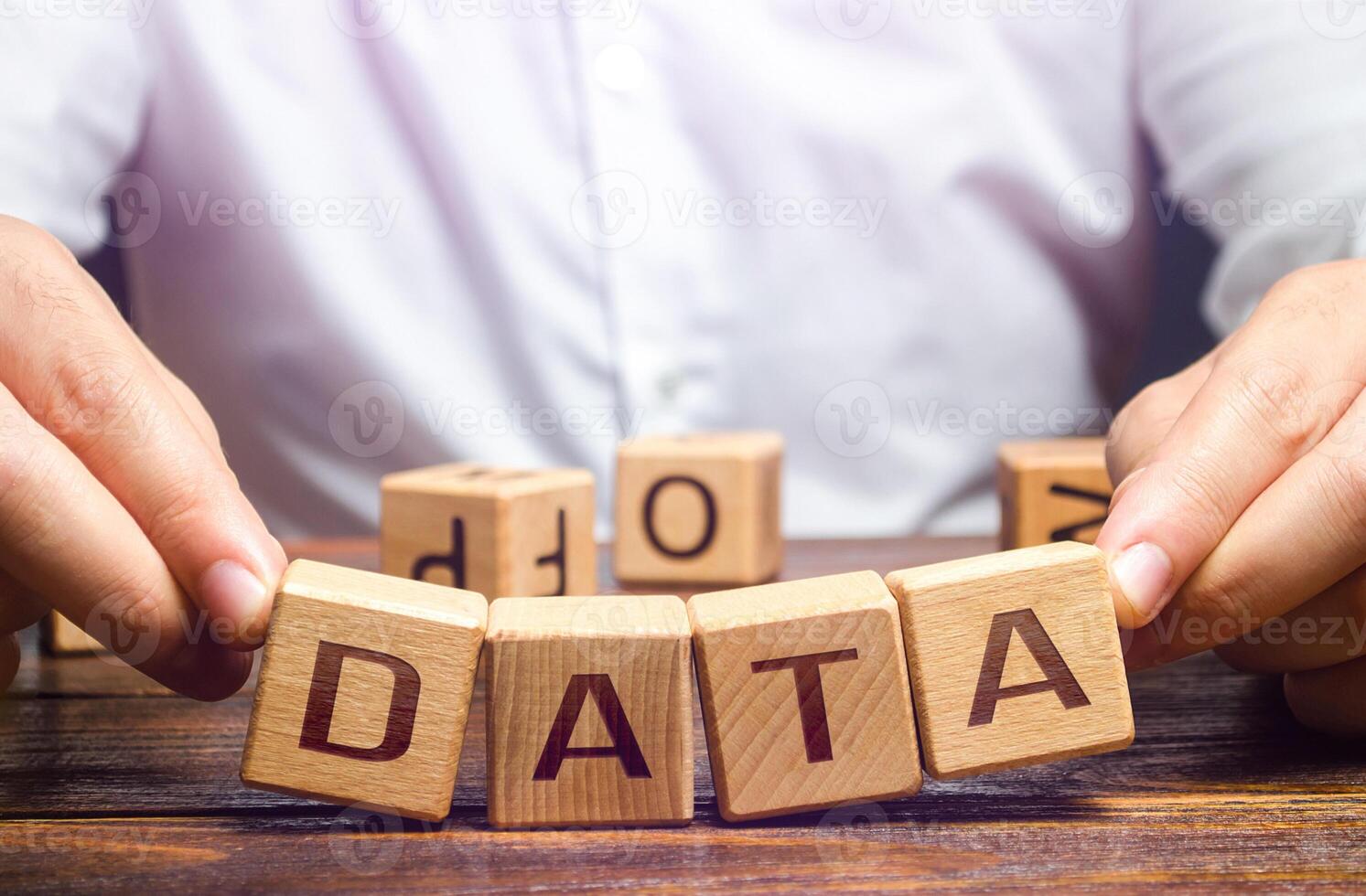 The man tries to pick up blocks with the word Data. Digital data integrity and security vulnerability concept. Fault tolerance, backup. Financial data leakage, password draining. Increased reliability photo
