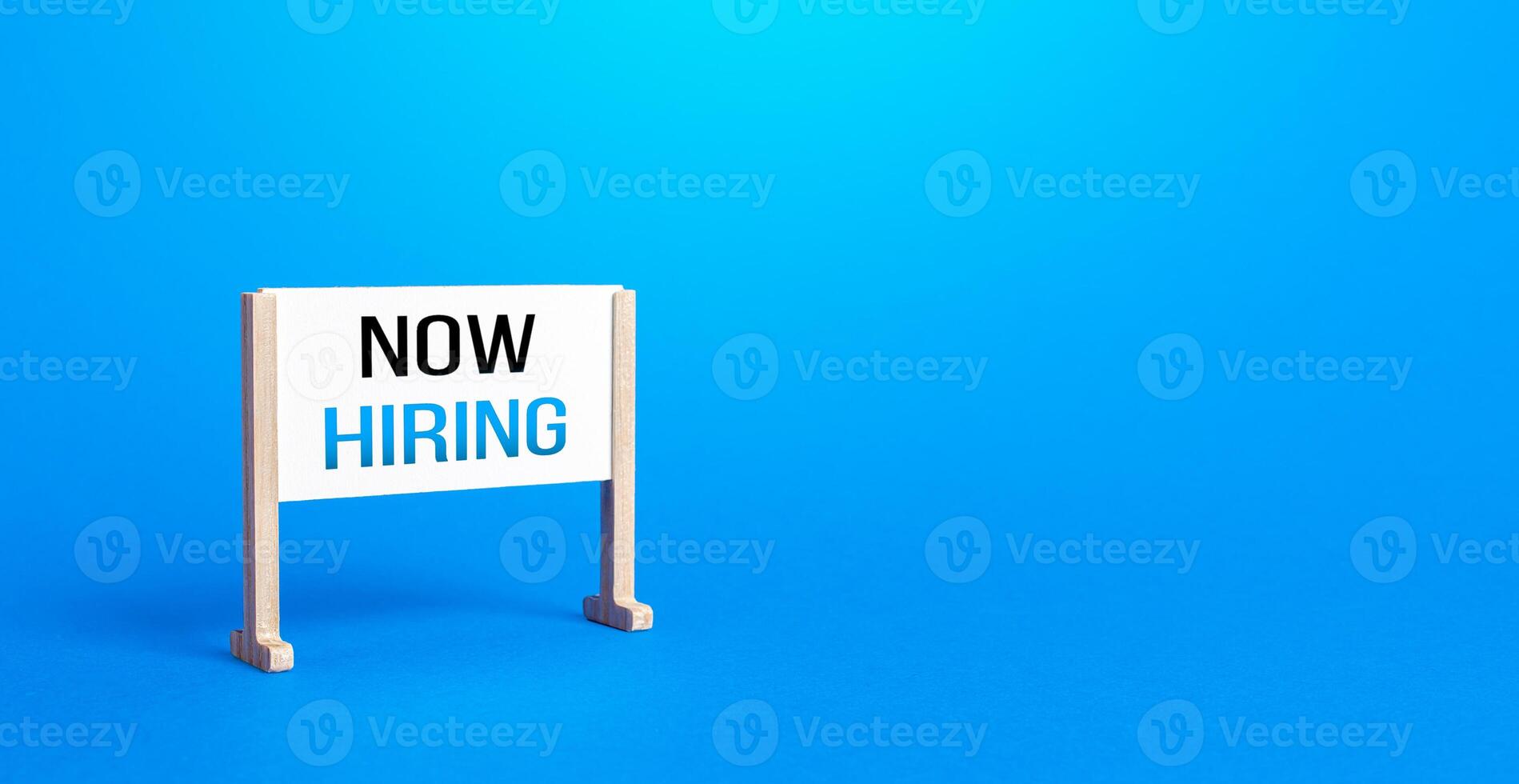 Notice board stand with words calling Now Hiring. Search and recruitment of new employees candidates for work. Search for specialists and professionals. Offers open vacancies positions. Minimalism photo