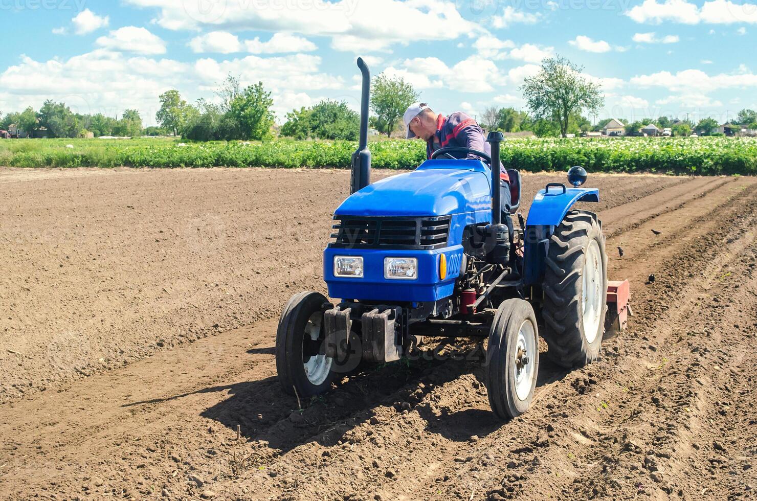 Farmer on a tractor loosens the soil with milling equipment. Loosening surface, land cultivation. Farming, agriculture. Plowing field. Use of agricultural machinery and to simplify and speed up work. photo