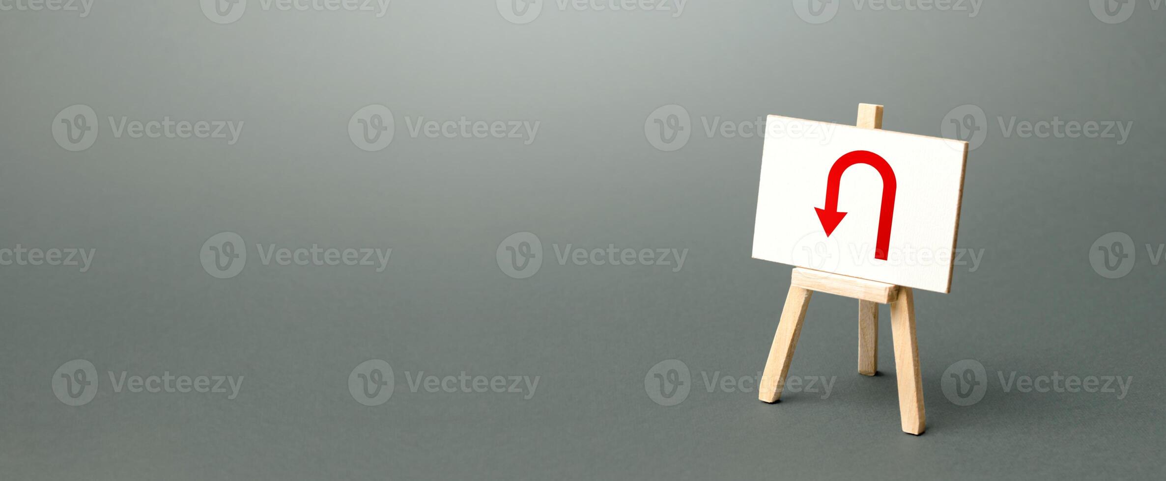 Easel with red arrow turning back. Tactical retreat for redeployment. Avoiding problems, reducing risks. Uncertainty, lack of purpose. Low discipline. Change plans, circumstances. Finding another way. photo