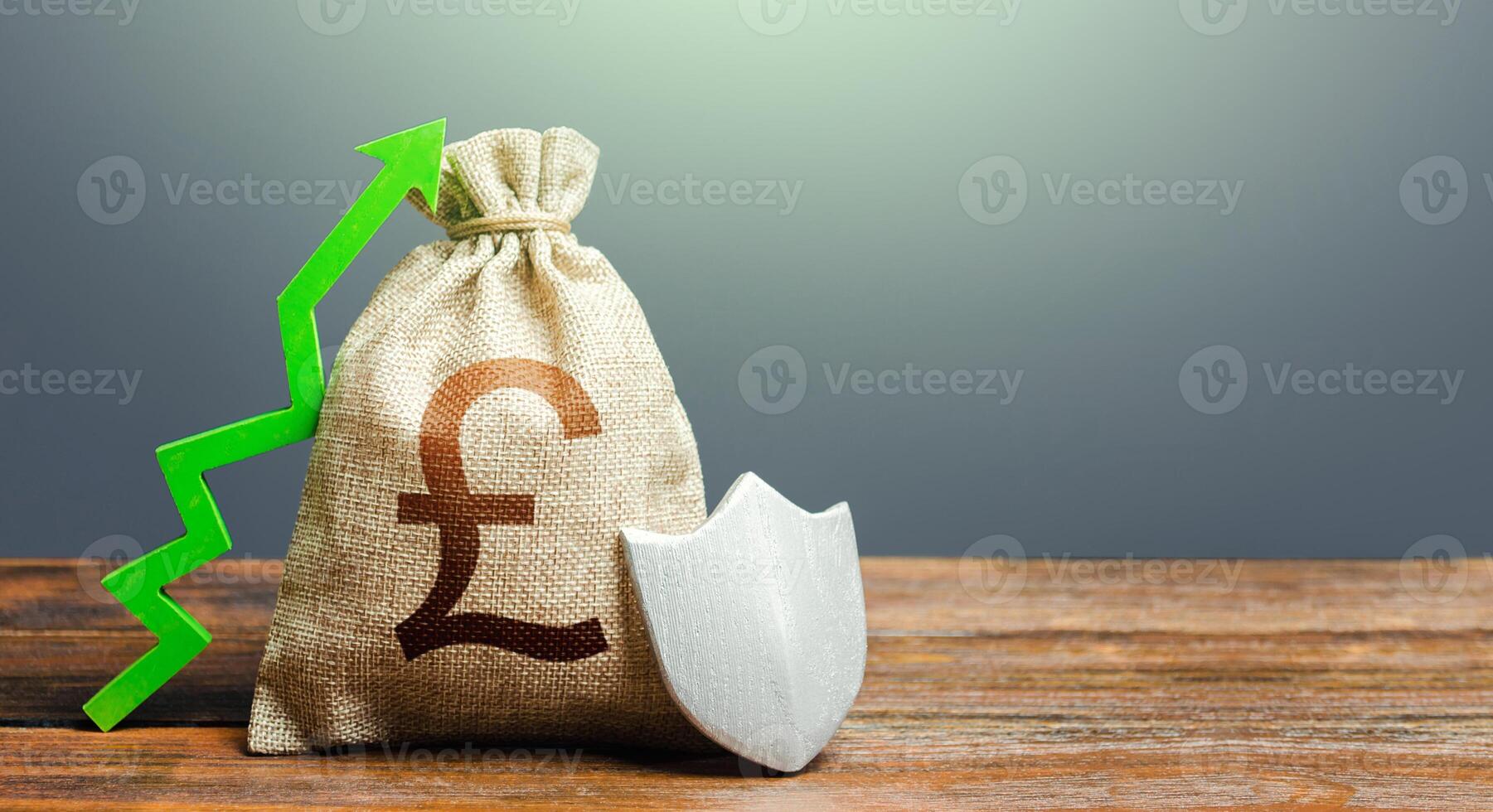 British pound sterling money bag with a shield and a green arrow up. Increasing maximum amount of guaranteed deposits insurance compensation. Safety security of investments, financial system stability photo