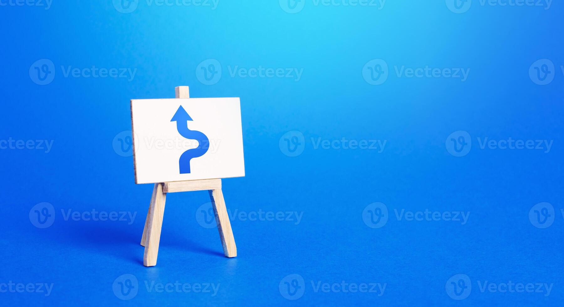 An easel with a blue arrow avoiding an obstacle. Maneuvering, taking right action. Deviation from the route, side mission. Purposefulness and perseverance, confident movement towards the assigned goal photo