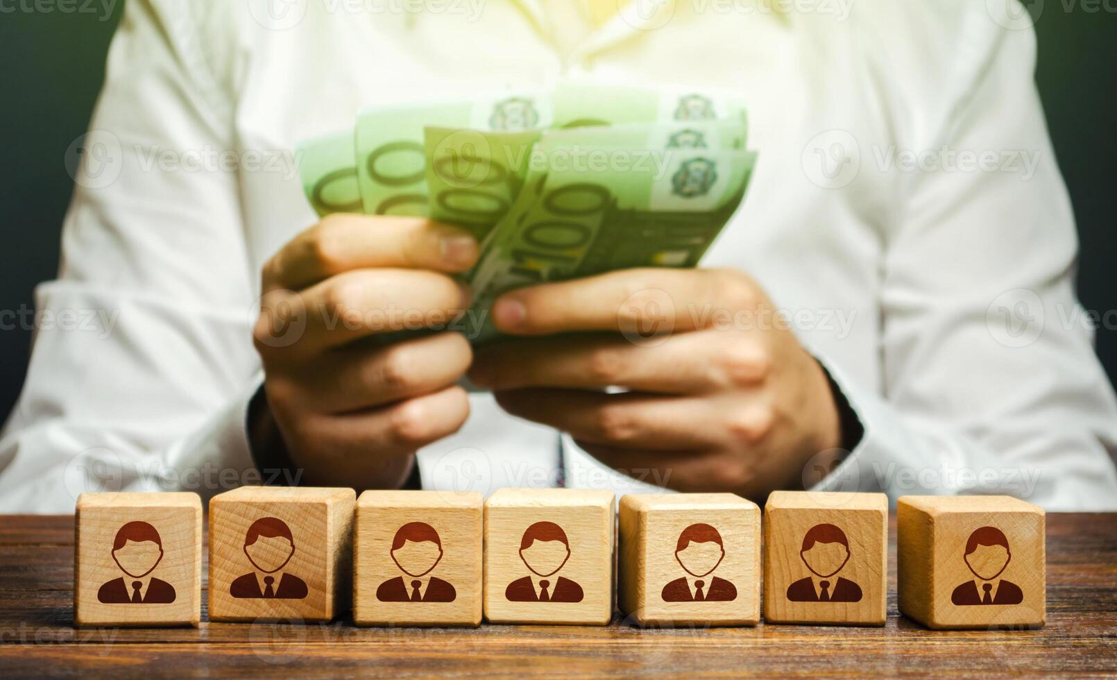 A man is counting euro money in his hands over blocks with symbols of employees. Wage fund. Accounting and budgeting. Payday. Expanding a profitable business, recruiting and training employees. photo