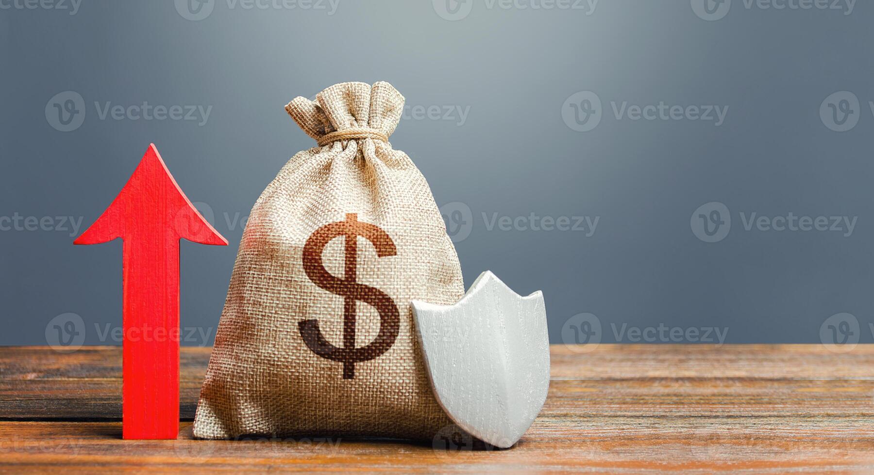 Dollar money bag with a shield and a red arrow up. Increasing the maximum amount of guaranteed insurance compensation for deposits. Safety security of investments, savings, financial system stability photo