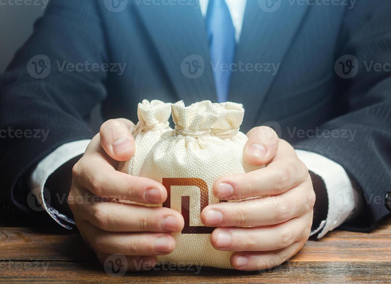 Businessman covers with hands israeli shekel money bags. Corrupt schemes. Profit collection and tax withholding. Hit jackpot. Capital. Budget absorption. Accumulation of funds, bank loan. Investments. photo