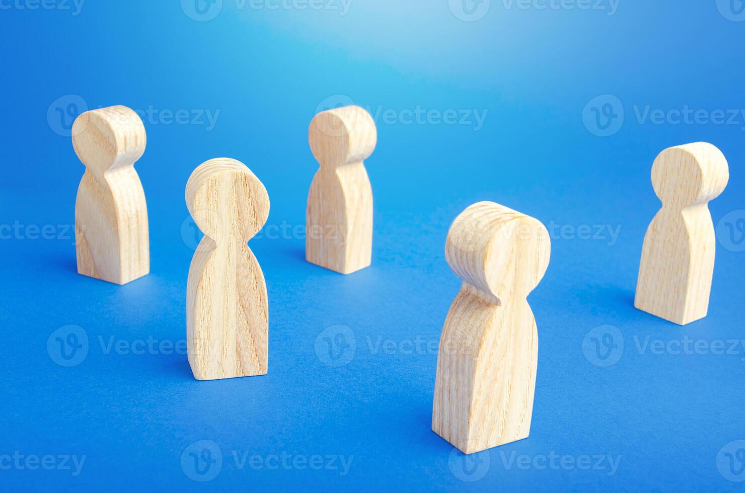 Wooden figurines of people stand on a blue background. Loneliness and disconnection. Safe spacing between persons, new normal. Faceless mass. Communication. Society public. Disunity concept. photo