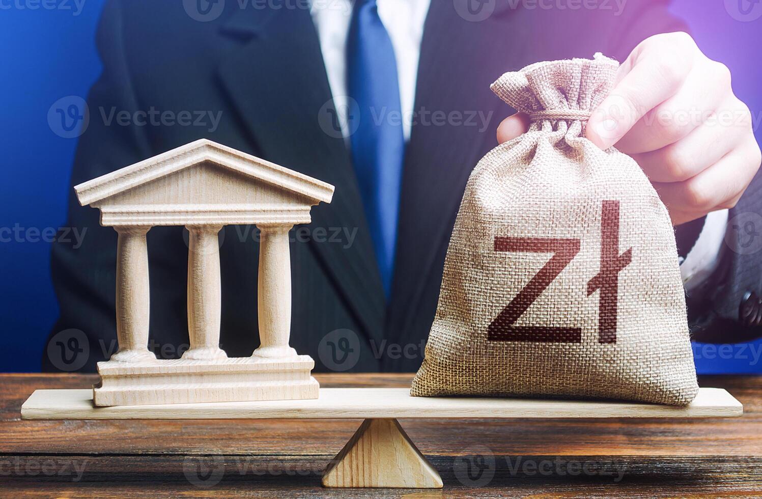 Businessman puts a polish zloty money bag on scales opposite to government state building. Lending to government projects. Payment of taxes and fees. Budgeting. Financing Social programs. Bank deposit photo
