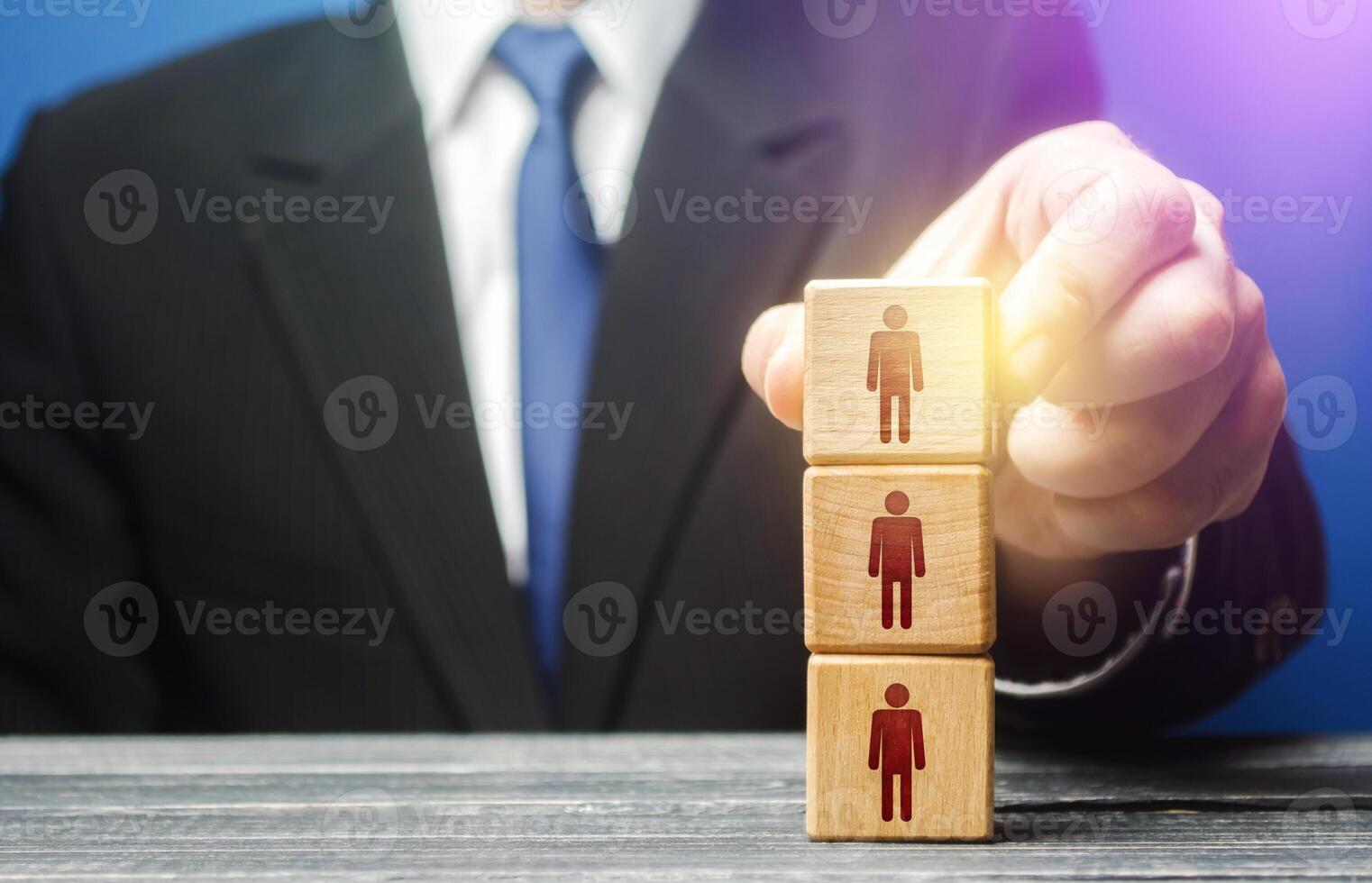 Business leader builds a people block tower. Definition of people in a hierarchical system. Meritocracy. Leadership skills, team personnel management. Company organization. Hiring, recruiting workers photo
