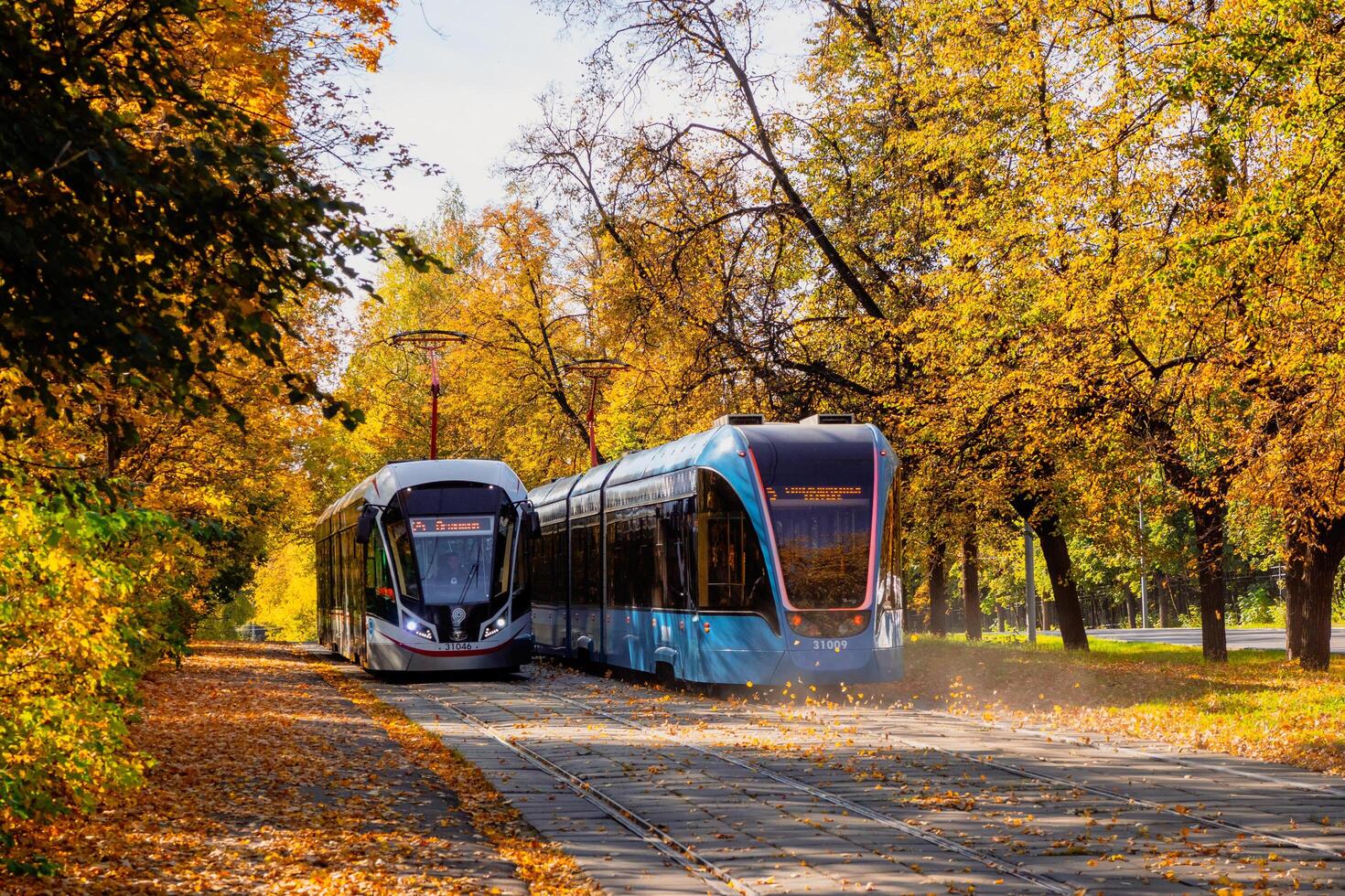 Russia, Moscow, September,30 2020 Two trams rides in the autumn tunnel. Tram rails in the corridor of the yellow autumn trees in Moscow photo