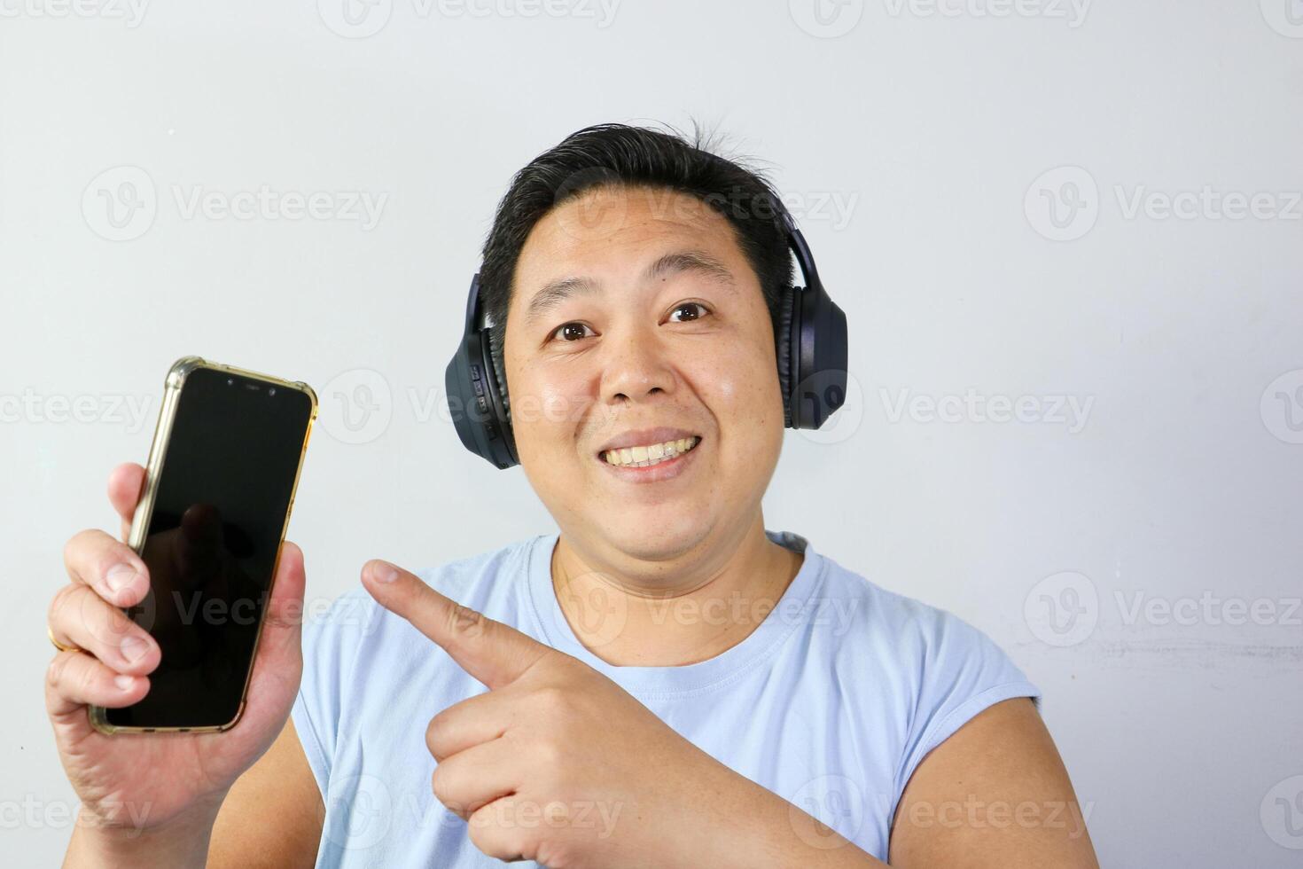 Happy man pointing at his smartphone while listing to music photo