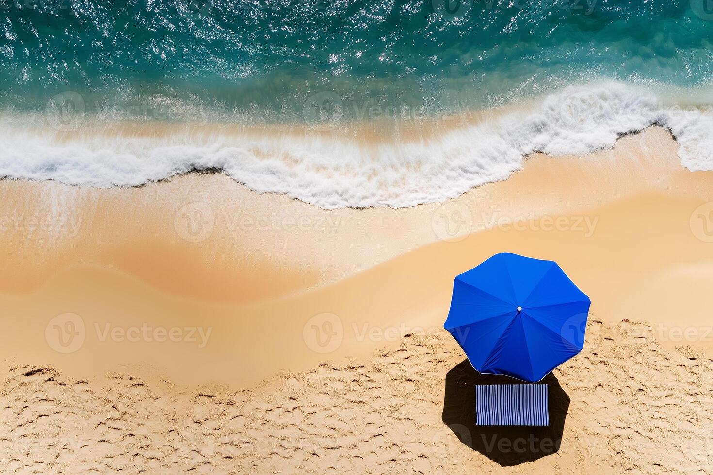a blue beach umbrella standing in soft golden sand near the shoreline photo