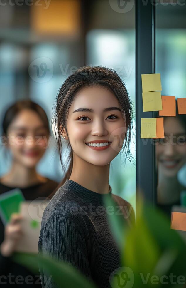 asian woman smiling in front of a glass door with sticky notes photo