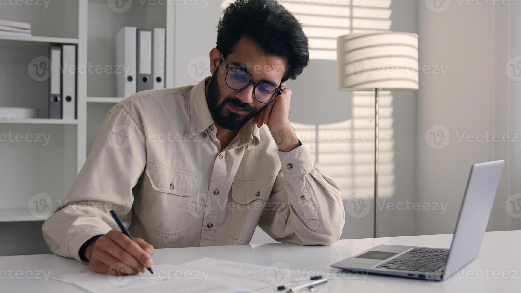 Tired bored Arabian Indian man businessman lazy employee manager boring job working with laptop studying write business project depression burnout fatigued overworked drowsy sleepy male guy at office photo