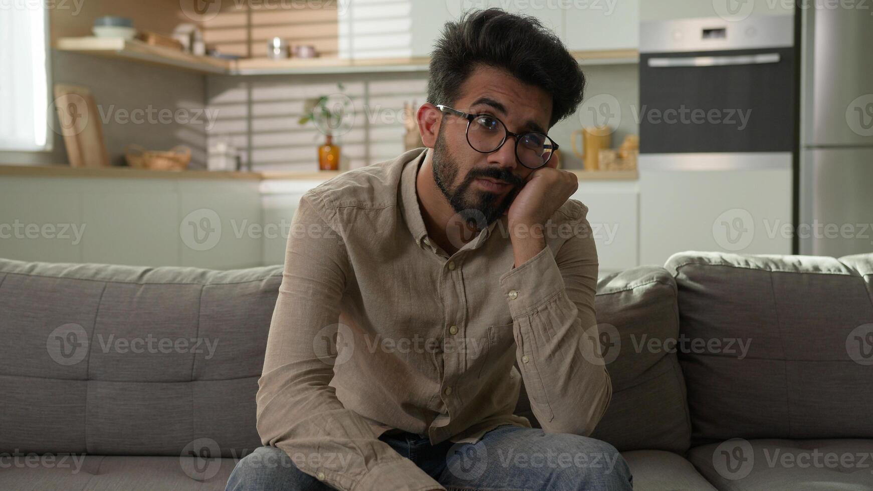 Pensive Indian Arabian man bored on home couch thinking deep in thoughts difficult decision tired exhausted thoughtful worried male boring weekend feel headache problem solution depression melancholy photo