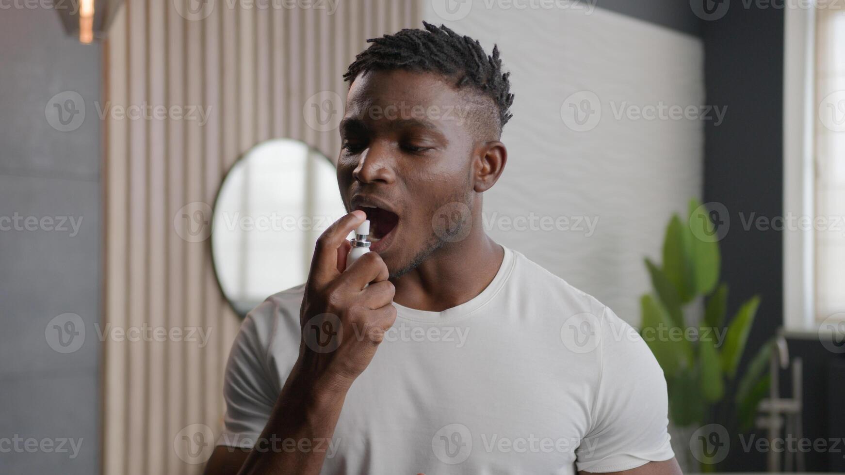 African American ethnic man applying fresh breath spray prevent stink morning hygiene of mouth preparing for date in bathroom smiling guy spraying freshener oral dental care product refresh breathing photo