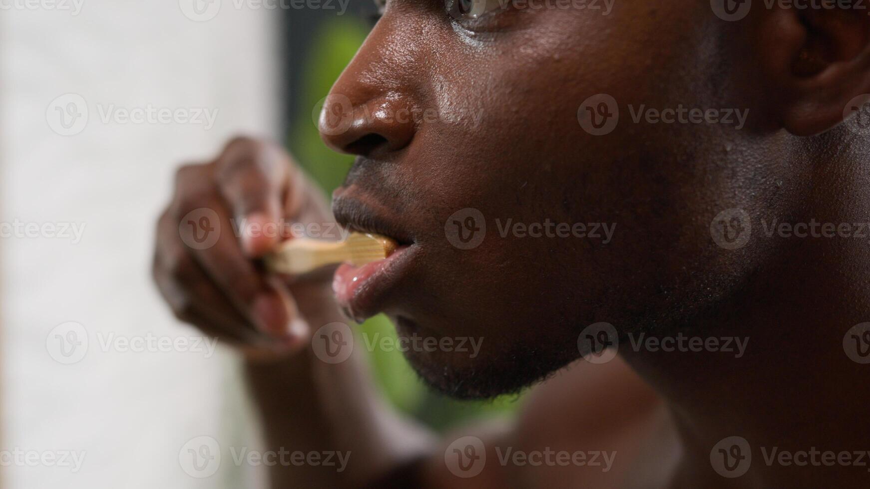 Moving shot African American male hold toothbrush with whitening toothpaste ethnic man brushing teeth cleaning gums oral care dentistry clean tooth refresh morning dental healthy hygiene in bathroom photo